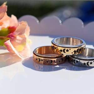May include: Three spinning rings with a moon and star design. The rings are silver, gold, and rose gold.