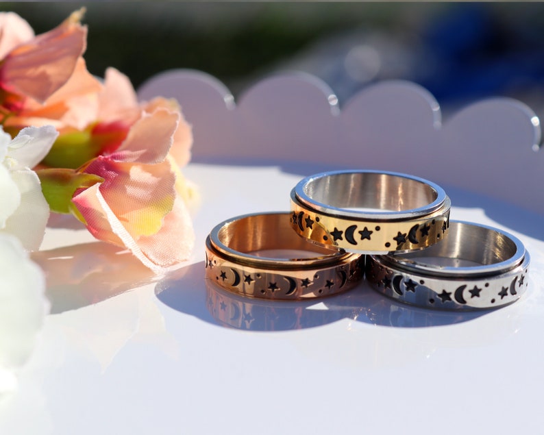 May include: Three spinning rings with a moon and star design. The rings are silver, gold, and rose gold.