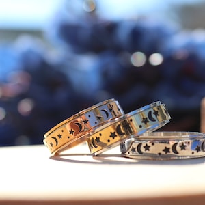 May include: Three gold and silver spinning rings with a moon and star design. The rings are stacked on top of each other.