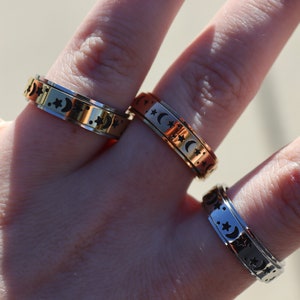 May include: Three silver, gold, and copper spinning rings with a moon and star design.
