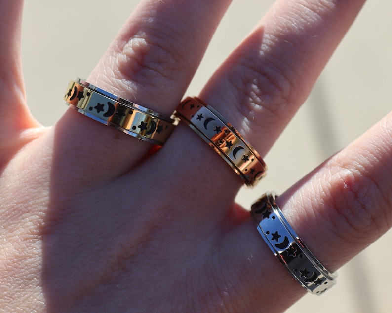 May include: Three silver, gold, and copper spinning rings with a moon and star design.