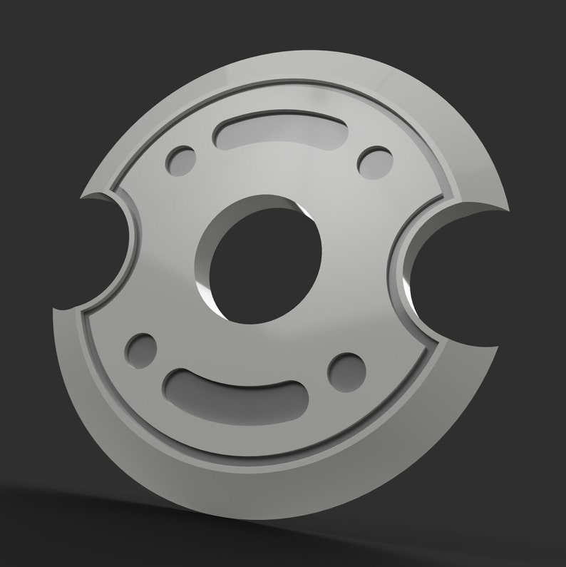 May include: A silver-colored, circular object with a central hole and several smaller holes and cutouts. The object has a smooth, metallic finish and is set against a dark gray background. The design is symmetrical and geometric.