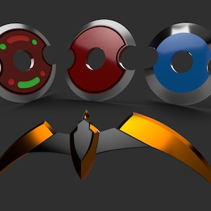 May include: Three circular, metallic-edged objects in red, blue, and maroon with a central hole and a curved cutout. Below, a gold and black stylized wing-shaped object is displayed against a dark gray background.