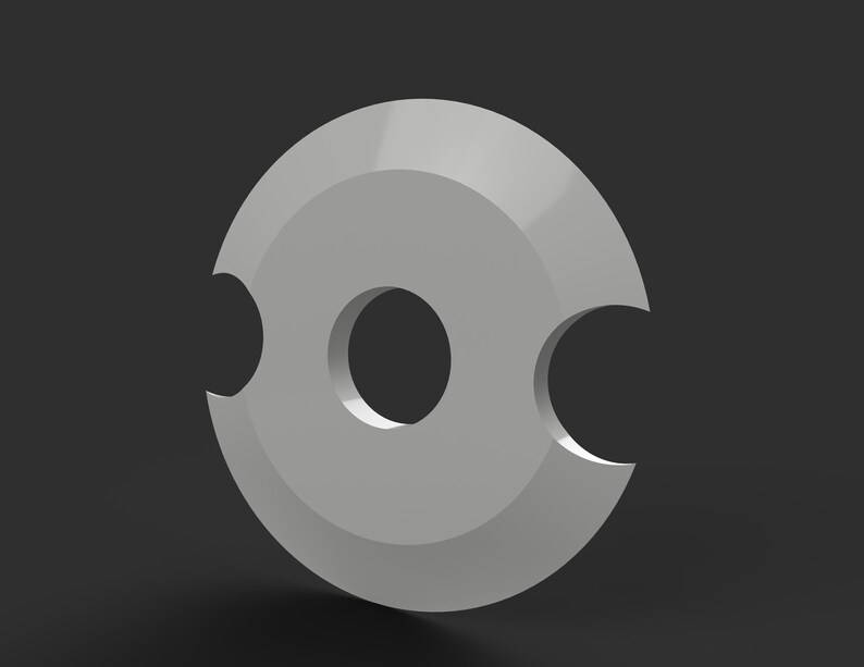 May include: A gray, circular object with a central hole and two curved cutouts on opposite sides. The object has a smooth, metallic appearance and is set against a dark gray background. The design is simple and geometric.