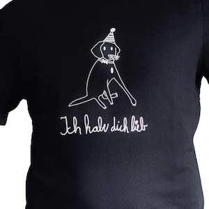 Könnte beinhalten: Schwarzes T-Shirt mit einer weißen Umrandung eines Hundes, der einen Partyhut trägt. Der Text "Ich habe dich lieb" steht unter dem Hund.
