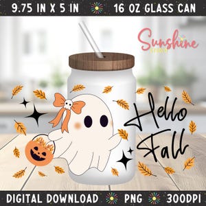 Puede incluir: Un vaso de vidrio de 473 ml con tapa de madera y pajita, con un gráfico de fantasma con lazo naranja y calavera, sosteniendo un cubo de calabaza. El diseño incluye hojas naranjas, estrellas negras y el texto Hello Fall.