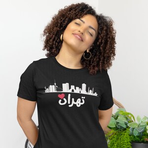 May include: Black t-shirt with a white graphic of a city skyline and the text "Teheran" with a red heart in front of it.