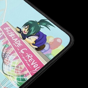 May include: A mousepad featuring a colorful anime-style illustration. The design includes a character with green hair and a blue outfit, along with the text "Beyblade G-REVOLUTION!!" on a pink banner. The background has a light blue sky and colorful balloons.