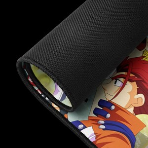 May include: Black mousepad with a detailed anime character illustration. The character has red hair, an orange jacket, and blue accents. The mousepad has a black, textured surface on the back.