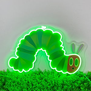 May include: Green neon sign shaped like a caterpillar with a friendly face. The sign is lit up and has a white outline.