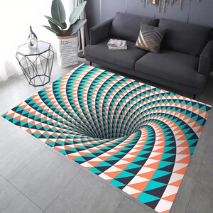 May include: A black, white, orange and blue patterned rug with a swirling, optical illusion design that creates the appearance of a hole in the floor.