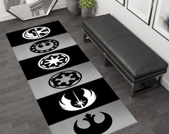 May include: A black and white Star Wars themed rug with a repeating pattern of the different Star Wars logos. The rug is on a gray floor and a black bench is in the background.