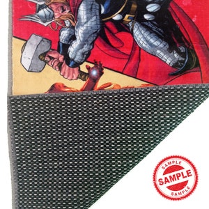 May include: A red, yellow, and black comic book style rug featuring a superhero with a hammer. The rug has a non-slip backing.