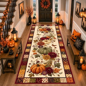 May include: A rectangular area rug featuring a cream-coloured centre decorated with a vibrant autumn pattern of orange, green, and white pumpkins, deep red dahlias, and fall leaves. The border consists of a patchwork of colourful floral squares.