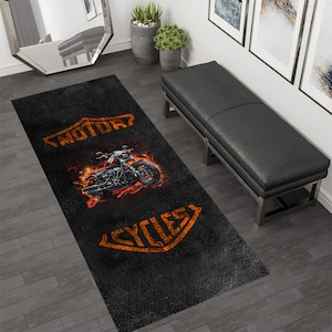 May include: Black and orange rug featuring a motorcycle graphic and the words "MOTOR CYCLES" in a vintage style font.