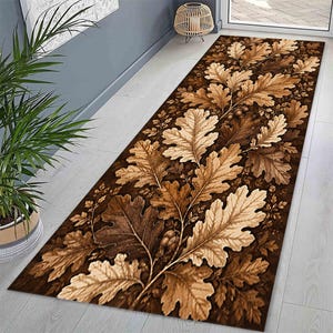 May include: A long rectangular runner rug featuring a detailed pattern of overlapping oak leaves and small acorns. The design displays a gradient of brown tones, ranging from deep dark chocolate to light tan, creating a dense botanical motif.