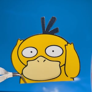May include: A yellow cartoon character with black eyes and a black beak, with yellow ears covering its ears. The character is looking to the right, with a surprised expression on its face.