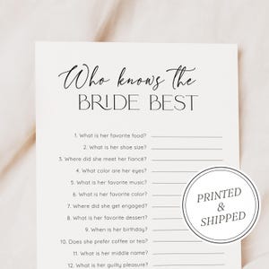 Puede incluir: Una tarjeta de juego de despedida de soltera de color crema titulada "Who Knows the Bride Best". La tarjeta presenta una lista de preguntas y una pegatina circular que dice "Printed & Shipped".