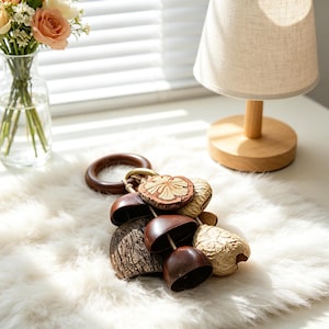 May include: A decorative hanging ornament featuring a dark brown wooden ring attached to a cluster of natural elements including smooth dark brown coconut shell segments, textured light tan dried seed pods, and a flat carved wooden flower disc.