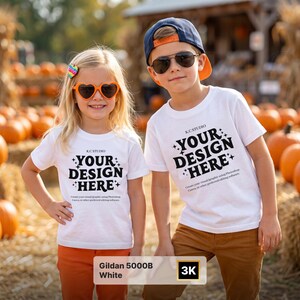 May include: Two white t-shirts with the black text "YOUR DESIGN HERE" and "K.C. STUDIO" printed on the front. The shirts feature a crew neck and short sleeves. The text includes small star icons and additional instructional text below.