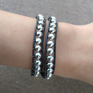 May include: A black leather wrap bracelet with silver beads.