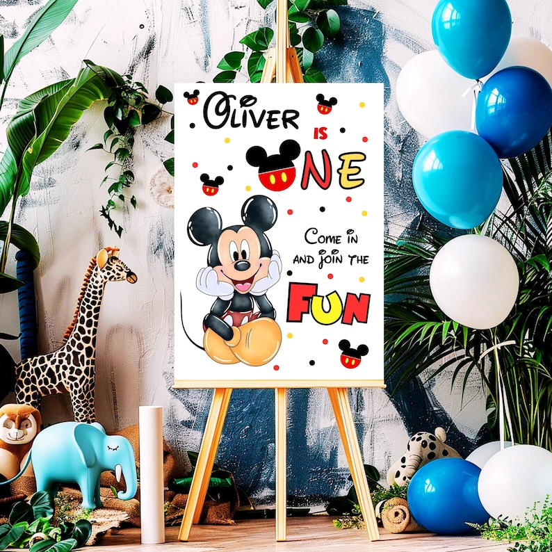 May include: A white sign on a wooden easel featuring Mickey Mouse and the text "Oliver is One." The sign includes the phrase "Come in and join the fun" and is decorated with red, yellow, and black accents. Balloons in blue and white are in the background.