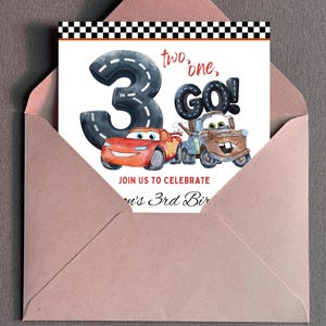 Puede incluir: Una tarjeta de invitaci&oacute;n de cumplea&ntilde;os con el n&uacute;mero 3 dise&ntilde;ado como una carretera, con el texto "two, one, GO!" e im&aacute;genes de coches de dibujos animados. La tarjeta est&aacute; dentro de un sobre rosa, con un dise&ntilde;o de bandera a cuadros en la parte superior.