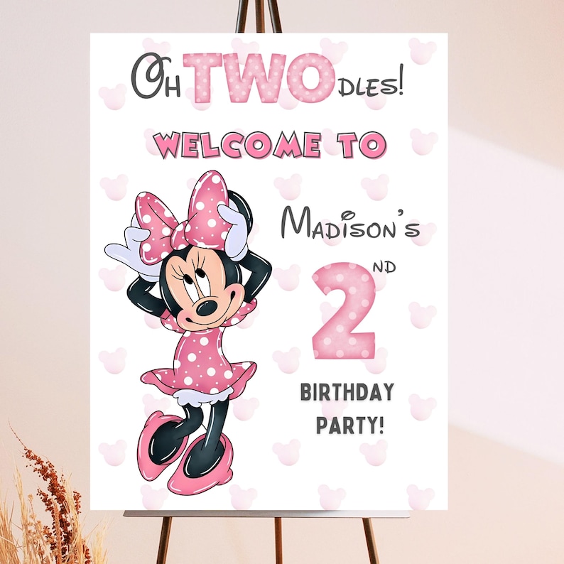 May include: A birthday party sign featuring Minnie Mouse. The sign reads "Oh TWO-dles! Welcome to Madison's 2nd Birthday Party!" Minnie Mouse is wearing a pink polka dot dress and bow. The background is white with pink heart shapes.
