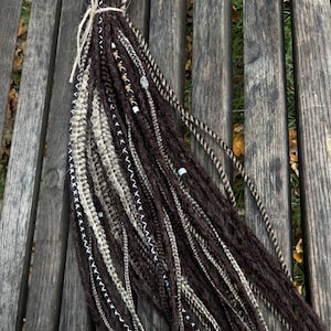 May include: A bundle of brown, beige and white synthetic dreadlocks with beads and decorative stitching.