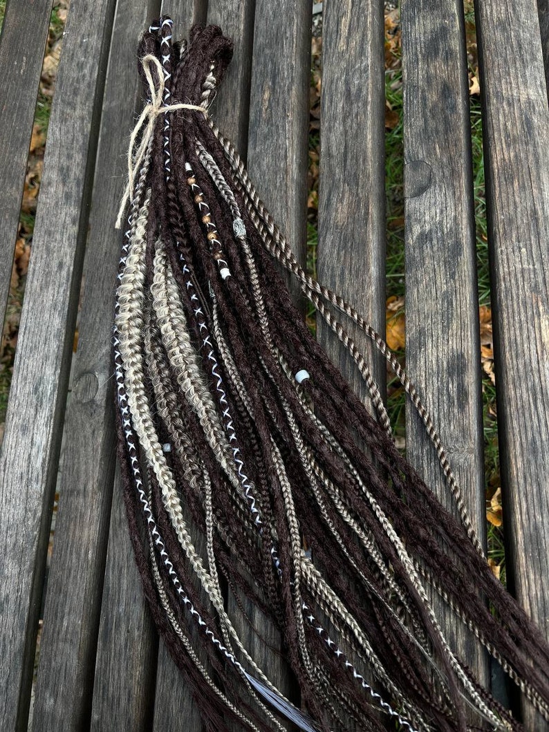 May include: A bundle of brown, beige and white synthetic dreadlocks with beads and decorative stitching.