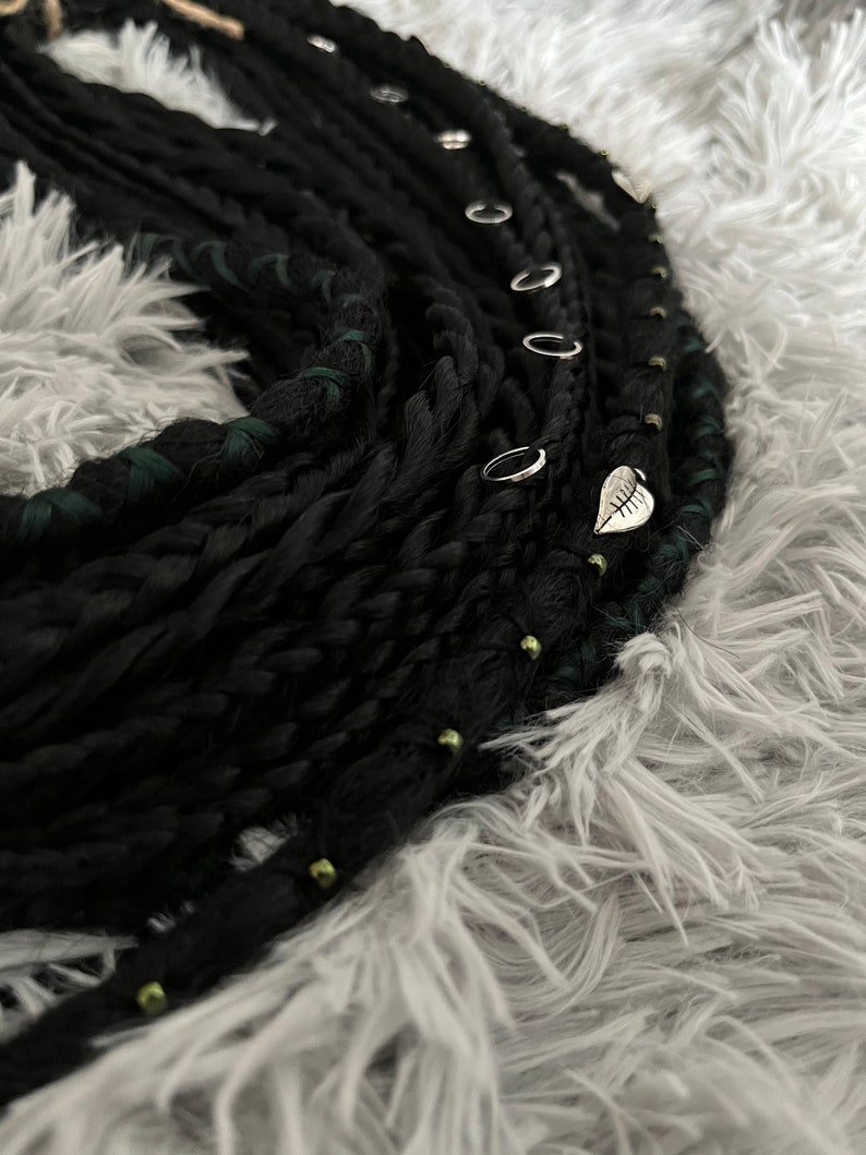 May include: Black and green synthetic dreadlocks with silver rings and a leaf charm.