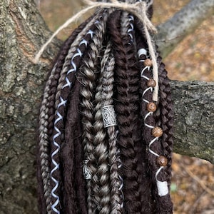 May include: A set of brown and grey synthetic dreadlocks with blue and white ribbon accents. The dreadlocks are tied together with twine and have wooden beads and metal beads.