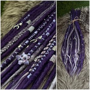 May include: A collection of purple and gray dreadlocks, some with silver accents and decorative charms. The dreadlocks are bundled together with twine, showcasing a unique and artistic hairstyle. The image highlights the texture and color variations.