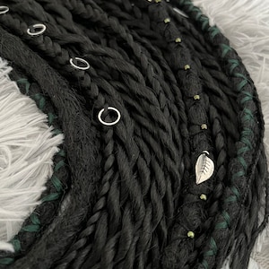 May include: Black synthetic dreadlocks with green accents and silver leaf charms.