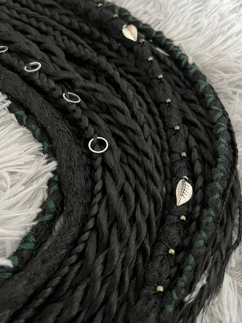 May include: Black synthetic dreadlocks with green accents and silver leaf charms.