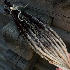 Könnte beinhalten: Ein Satz brauner und blonder synthetischer Dreadlocks mit goldenen Blattakzenten. Die Dreadlocks sind mit einem braunen Band zusammengebunden.