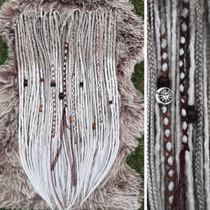 Peut inclure: Un ensemble de dreadlocks synthétiques gris et blancs avec des accents bruns et blancs. Les dreadlocks sont décorées de perles et de breloques.