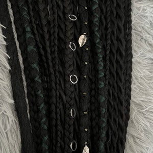 May include: Black synthetic dreadlocks with green accents and silver rings and leaf charms.