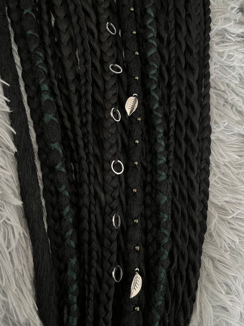 May include: Black synthetic dreadlocks with green accents and silver rings and leaf charms.