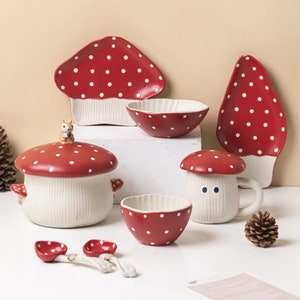 Pu&ograve; includere: Un bizzarro set di stoviglie in ceramica a tema fungo. Il set include piatti, ciotole, una tazza, una pentola con coperchio e cucchiai. I pezzi sono rossi con pois bianchi e basi bianche. Una statuina di scoiattolo adorna il coperchio della pentola.