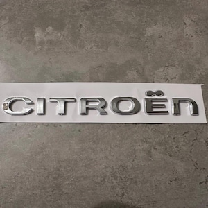 May include: A silver metal emblem with the word "CITROËN" in all caps.