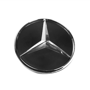Op de afbeelding: Een zilveren en zwart Mercedes-Benz logo met een driepuntige ster.