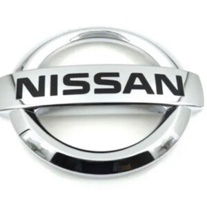 Peut inclure: Un emblème Nissan chromé, avec le nom de la marque en lettres majuscules noires et grasses. L'emblème a un design circulaire avec une barre horizontale au centre, créant un logo distinctif et reconnaissable.
