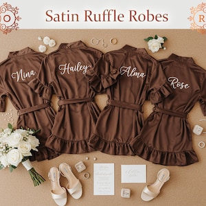 May include: Four brown satin ruffle robes with personalized names, displayed with bridal accessories. The robes have ruffled sleeves and hems, with matching belts. The image includes a bouquet, shoes, and jewelry.