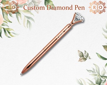 May include: A rose gold pen with a large diamond-shaped clear crystal at the top. The pen is engraved with the text "Custom Text".