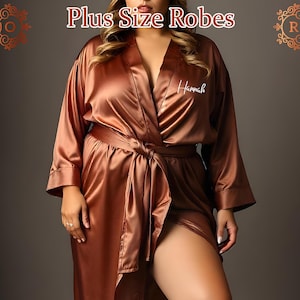 May include: A long, brown satin robe with a tie belt and a white embroidered name "Hannah". The robe has long sleeves and a shawl collar. Plus Size Robes.