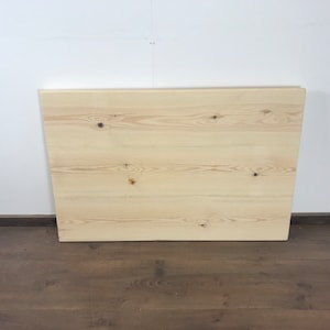 May include: A light wood tabletop with a natural finish. The tabletop is made of several planks of wood that have been joined together. The wood has a light grain pattern and some knots.