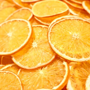 Dozens of dried orange slices beautifully arranged on a light surface. These dried citrus slices are ideal for rustic home decor, gift wrapping, and sustainable crafts using natural fruits.