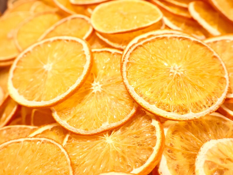 Dozens of dried orange slices beautifully arranged on a light surface. These dried citrus slices are ideal for rustic home decor, gift wrapping, and sustainable crafts using natural fruits.