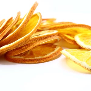 Close-up of handcrafted dried citrus slices showing vibrant texture and authentic orange color. These orange dried slices are excellent as a cocktail garnish, for cake decorating, or as flavorful dry fruit snacks. Made from natural dry oranges, they add a unique citrus aroma to drinks and dishes while being 100% vegan, vegetarian-friendly, and perfect for creative, eco-friendly food styling.